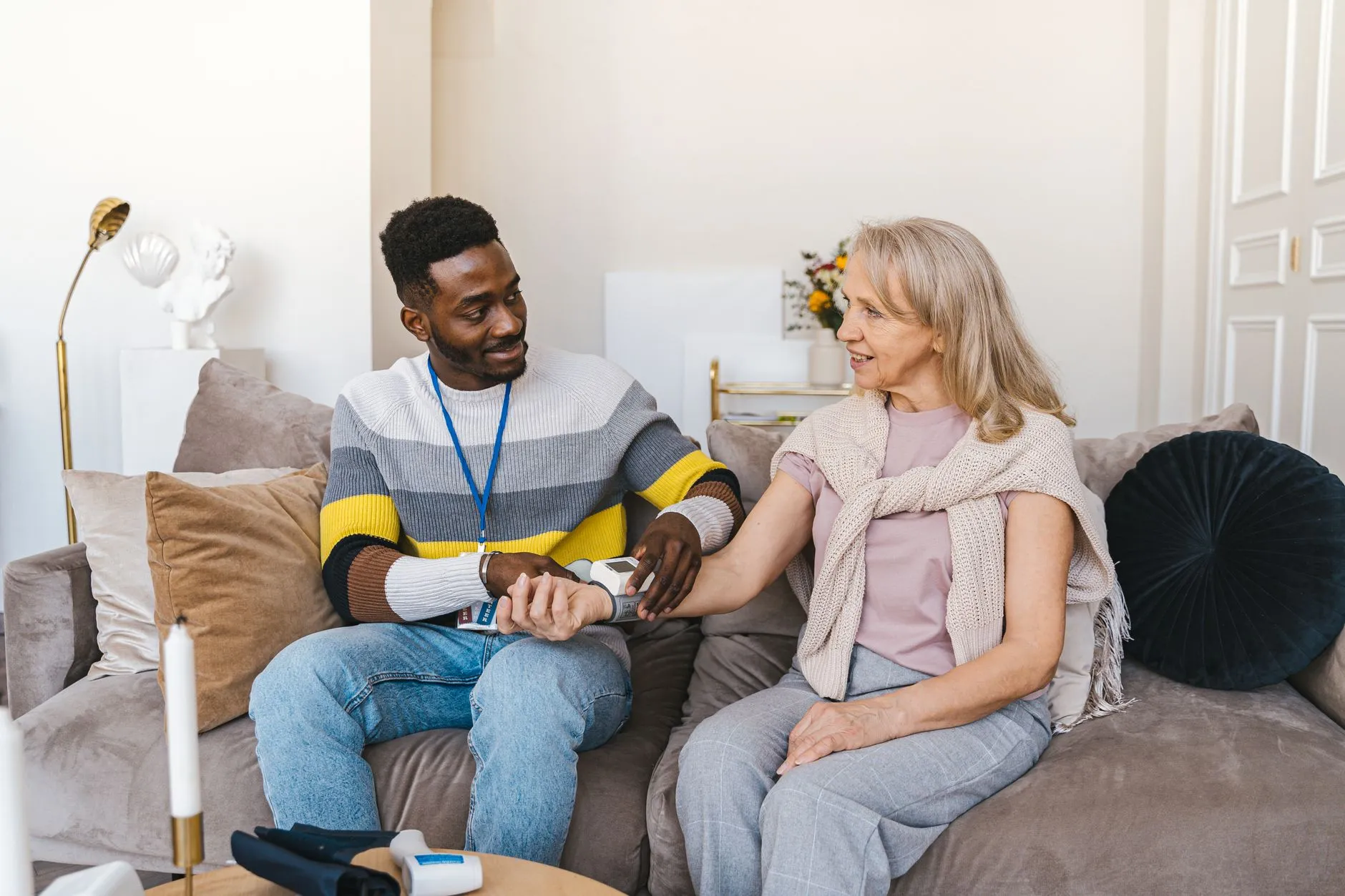 A nurse checking an older woman's blood pressure in her living room