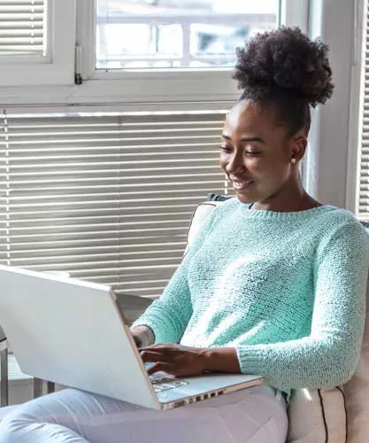 A care worker taking an online course on a laptop by a window